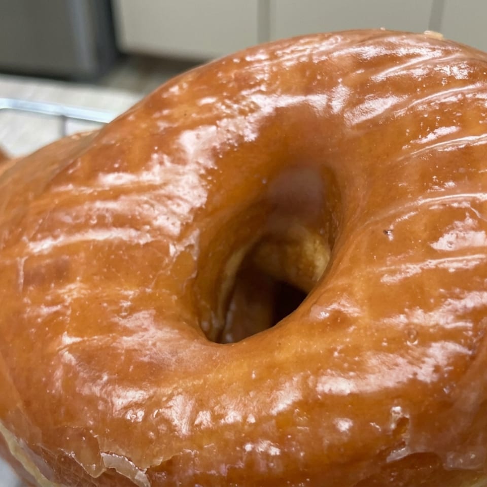 Close-up of glossy glazed ring doughnuts cooling on a wire rack.